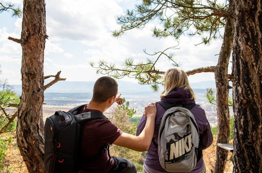 A couple enjoying a break on a forest bench with a scenic view, perfect for nature and lifestyle themes.