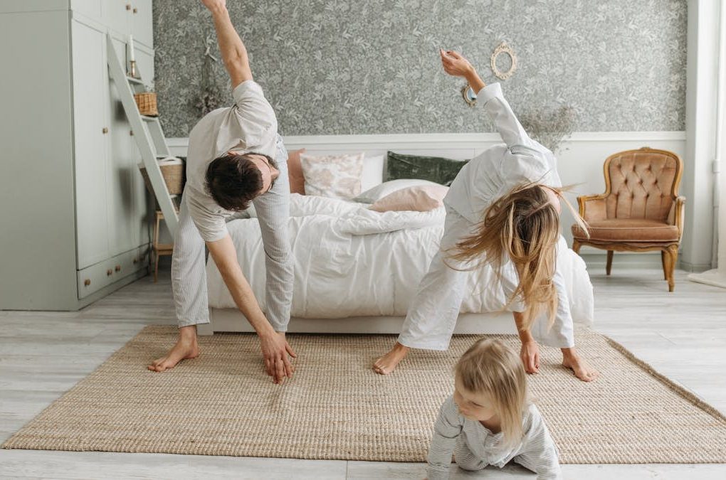 A family stretches together in a cozy bedroom, enjoying morning activities.