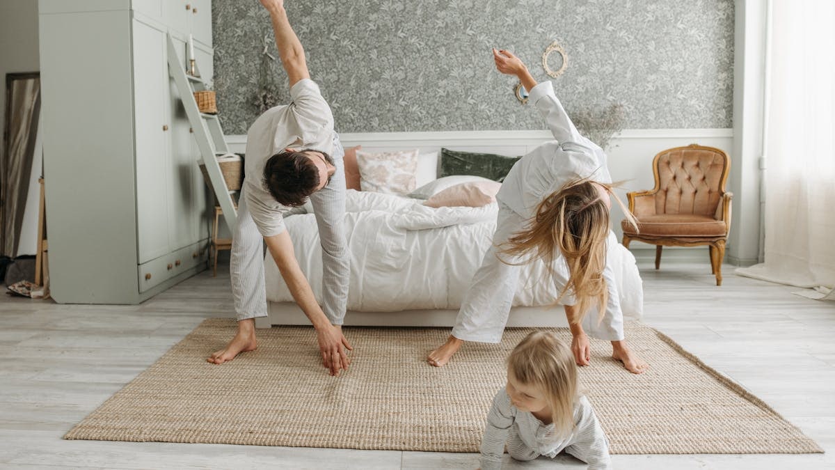 A family stretches together in a cozy bedroom, enjoying morning activities.